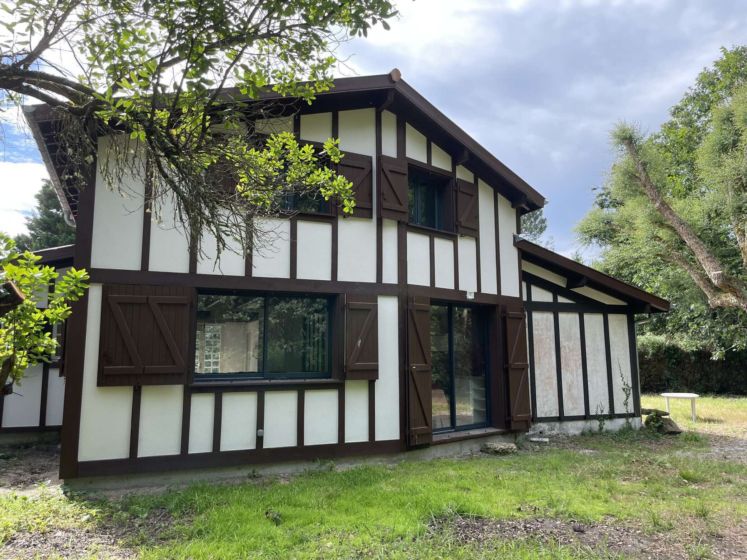 A two-story building with a combination of white and dark brown siding, large windows, and a visible door.