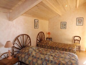 Ein Schlafzimmer mit zwei Holzbett, einem Nachttisch, einem Stuhl und einer Lampe.