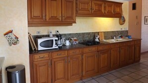 A kitchen with wooden cabinets, a microwave, a sink, and a trash can. - Peaceful villa with pool, pets welcome - 8 guests (Vielle-Saint-Girons)