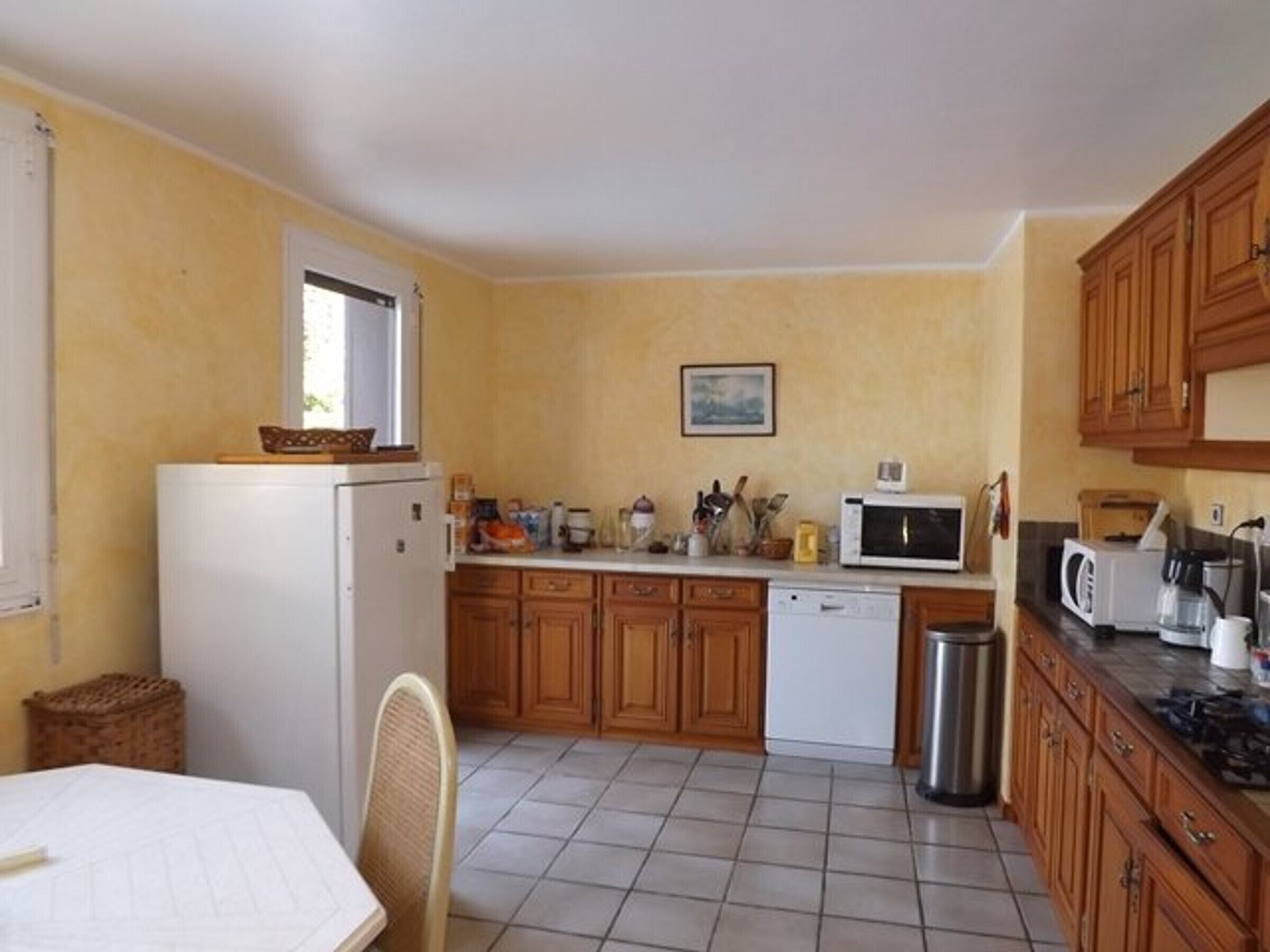 A compact kitchen with a refrigerator, microwave, and wooden cabinets.
