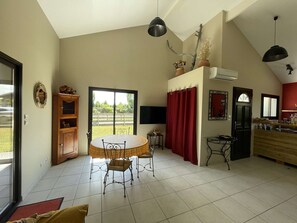 Una cocina amplia con comedor, un ventanal grande y una cortina roja.