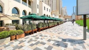 A hotel with outdoor seating, potted plants, and a tiled walkway. - Premium 3BR plus maid room -Beachfront -Monthly Stay (Dubai)
