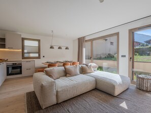 Ein modernes Schlafzimmer mit einem großen Bett, einer Küchenzeile und einer Glastür zum Balkon.