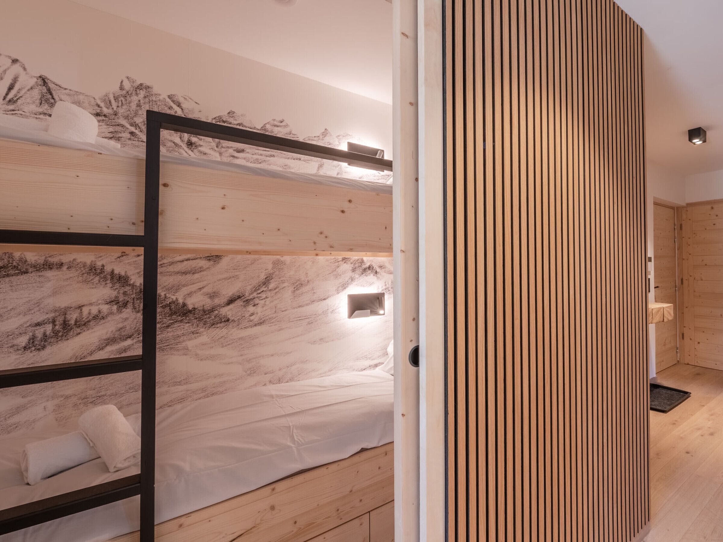 Un dormitorio moderno con cama, pared de paneles de madera y un mural de montañas.