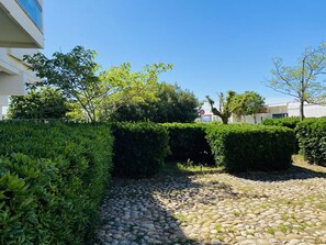 Ein gepflasterter Innenhof mit einem Kiesweg, ordentlich geschnittenen Hecken und einem Gebäude im Hintergrund.
