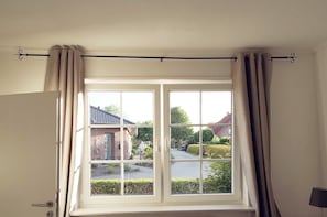 Ein Zimmer mit Fenster, Vorhängen und Tür.