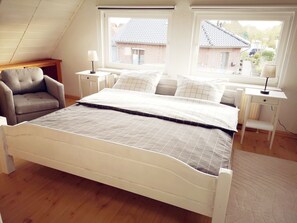 Une chambre à coucher avec un lit, une chaise, deux tables de chevet et une fenêtre.