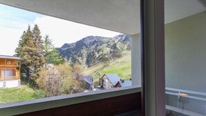 Un balcon avec vue sur une montagne, un bâtiment en bois et un arbre.