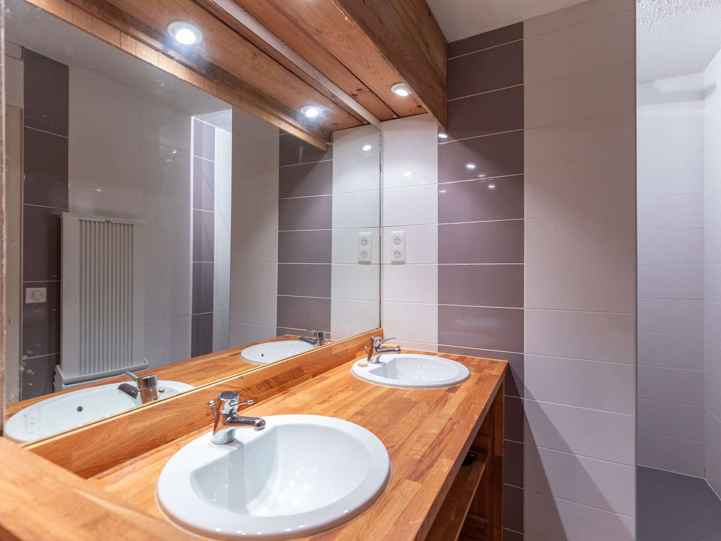 Ein Badezimmer mit zwei Waschbecken, einem Holzlager und einem großen Spiegel.