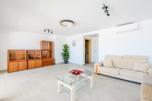 A modern living room with a glass coffee table, wooden cabinets, a beige sofa, and a potted plant. - Villa Montinho Vista (Monchique)