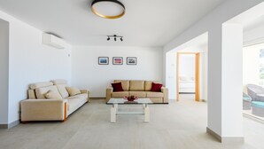 A spacious living room with a beige sofa, a glass coffee table, and a modern ceiling light fixture. - Villa Montinho Vista (Monchique)