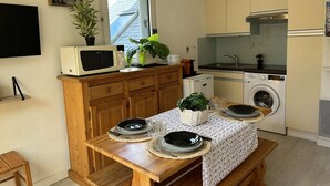 Une cuisine compacte équipée d’un four à micro-ondes, d’un lave-linge et d’un évier.