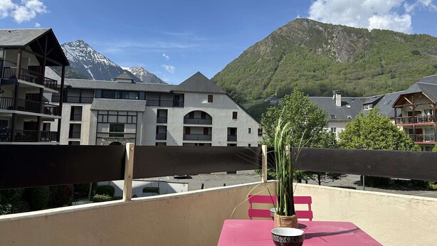 Un balcon avec une table, des chaises et un pot de fleurs.