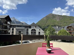Ein Balkon mit Tisch, Stühlen und einer Topfpflanze.