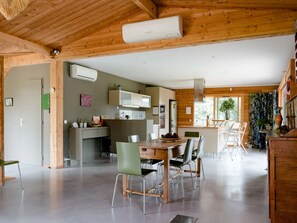 Eine moderne Küche mit integrierten Geräten, ein Essbereich mit Holztisch und Stühlen sowie ein großes Fenster für natürliches Licht.