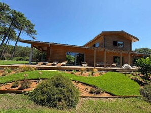 Ein modernes, zweistöckiges Haus mit überdachter Terrasse und gepflegtem Garten.