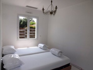 Une chambre avec deux lits, une fenêtre et un lustre.