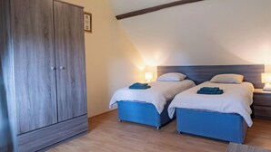 A bedroom with two beds, a wardrobe, and a sloped ceiling.