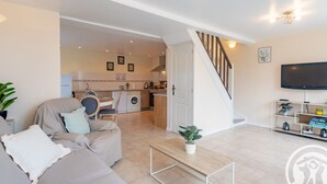 A living room with a sofa, a coffee table, a TV, and a staircase leading to a kitchen.
