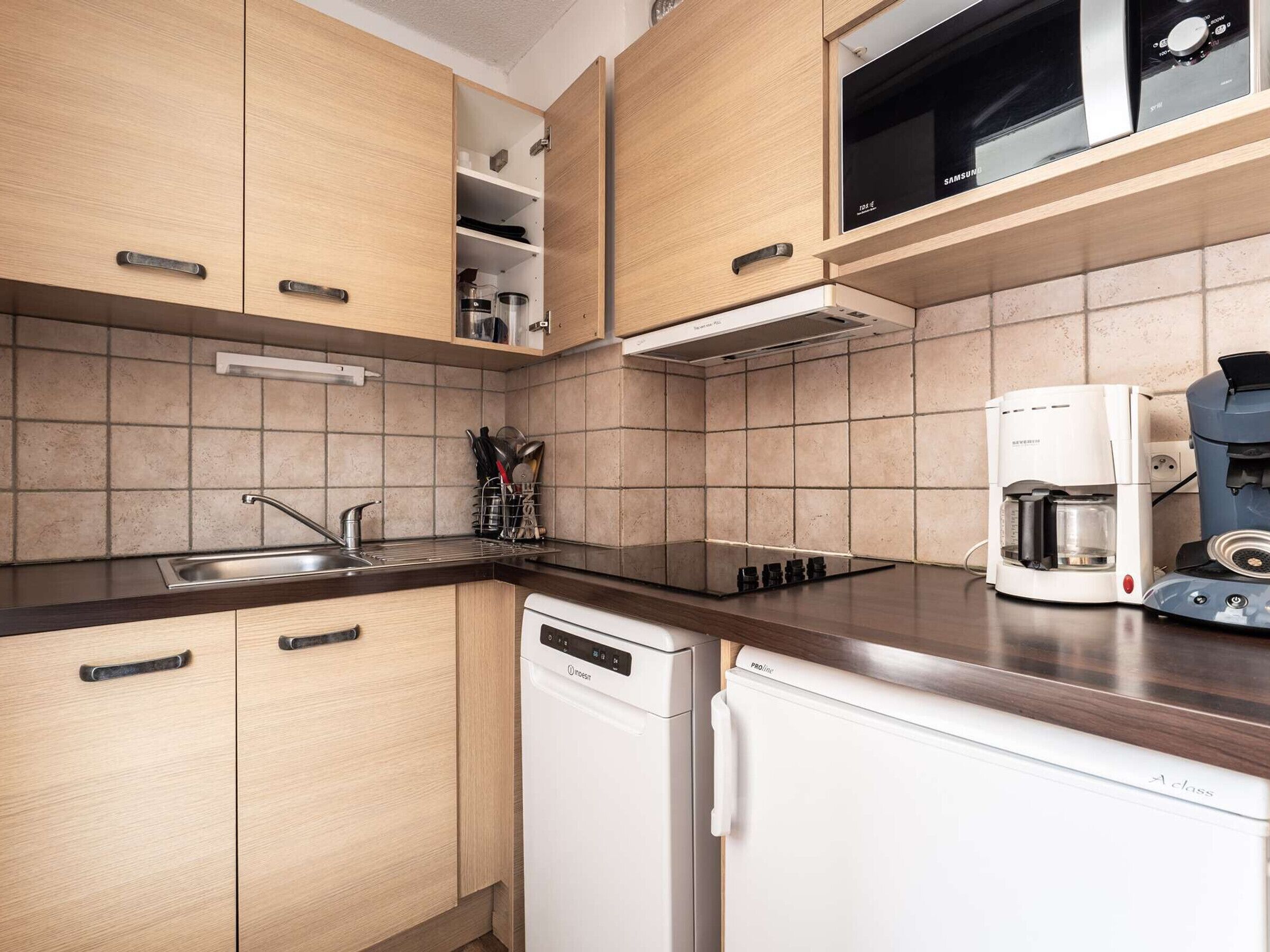 A modern kitchen with wooden cabinets, a dishwasher, a coffee maker, and a microwave.