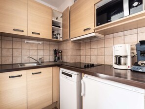 Eine moderne Küche mit Holzausstattung, einem Geschirrspüler, einer Kaffeemaschine und einer Mikrowelle.