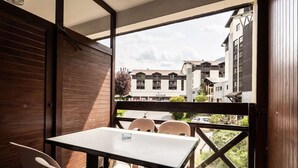 Un balcón con mesa y sillas, con vistas a un edificio con varias ventanas y balcones.