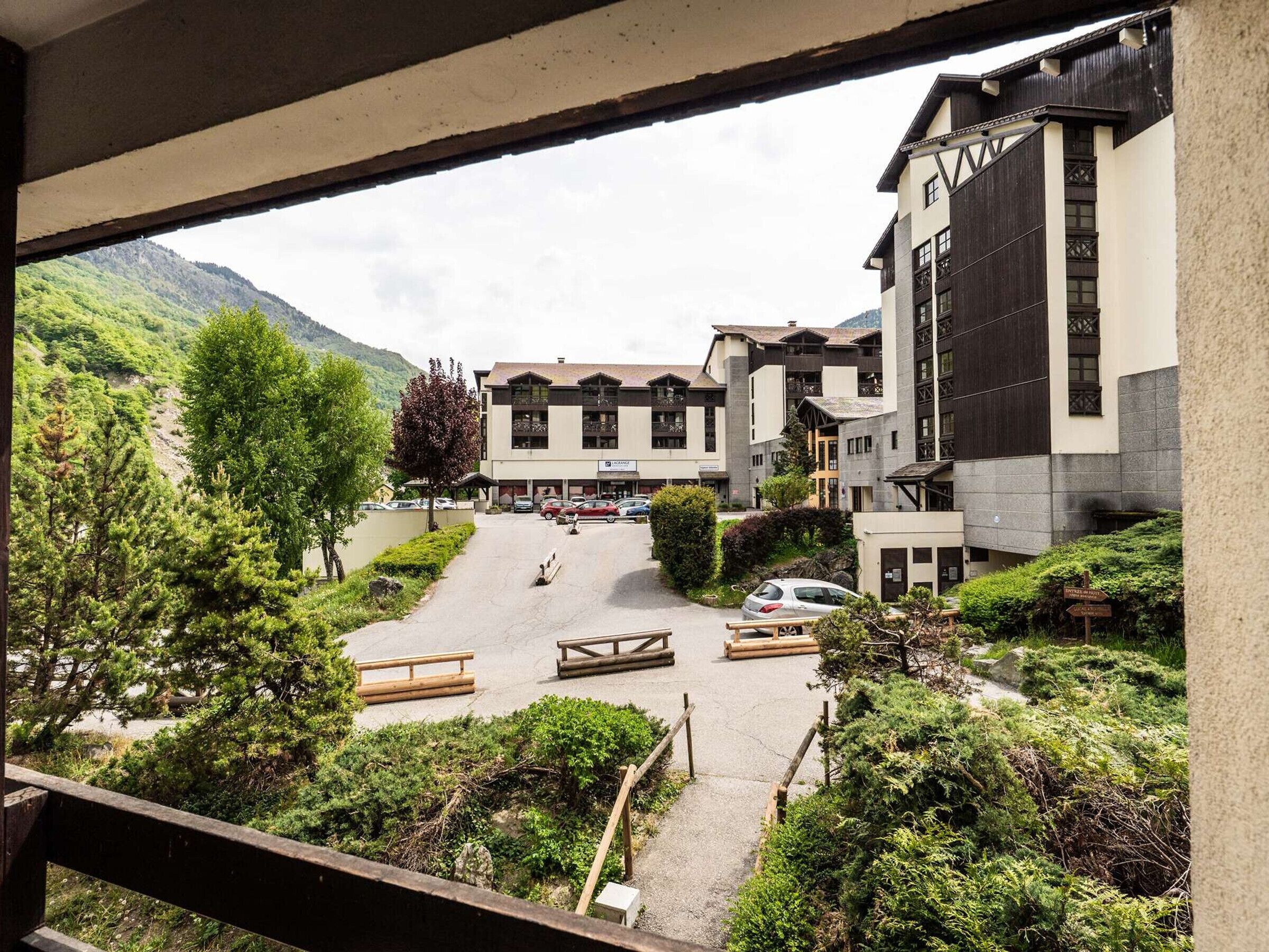A hotel with a parking area, outdoor seating, and a view of a mountainous landscape.
