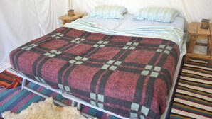 Una cama con un edredón escocés, una almohada a rayas y una alfombra estampada.