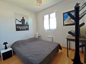 Une chambre à coucher avec un lit, une affiche, une fenêtre et un meuble pour la télévision.