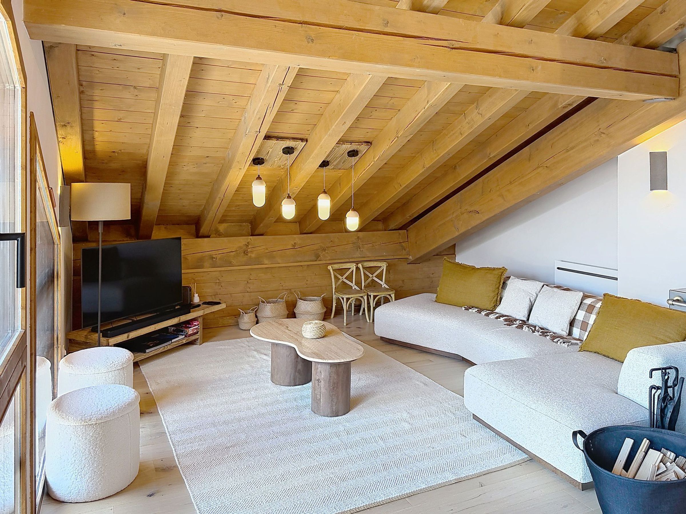 Ein Loft-Zimmer mit Holzboden, einer Couch, einem Fernseher, einem Couchtisch und einem Kamin.