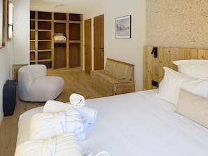 A bedroom with a bed, a wooden headboard, a wardrobe, a chair, and a small table. - Elegant apartment, mountain view - 10 guests (Montvalezan-La Rosière)