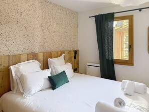 Une chambre d’hôtel avec un lit, des oreillers, une fenêtre avec des rideaux et une tête de lit en bois.