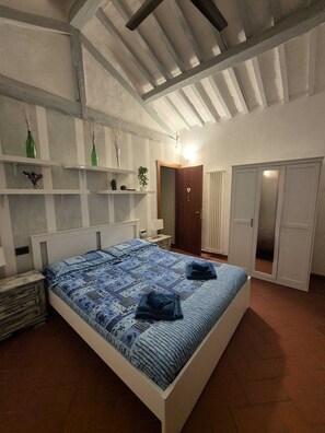 Ein Schlafzimmer mit Bett, Kleiderschrank, Nachttisch und Regalen mit Dekoration.