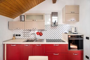 Een keuken met een houten plafond, een roestvrijstalen oven en rode keukenkastjes.