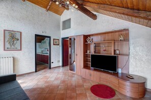 Een ruime woonkamer met een houten tv-meubel, een flatscreen televisie en een rood vloerkleed.