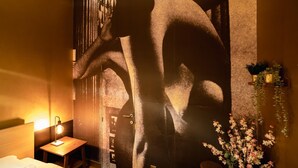 A hotel room with a large wall mural, a bedside table with a lamp, and a potted plant. - 1-bedroom Apartment in National Residence (Antwerp)