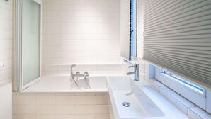 A bathroom with a bathtub, a sink, and a shower. - 1-bedroom Apartment in National Residence (Antwerp)