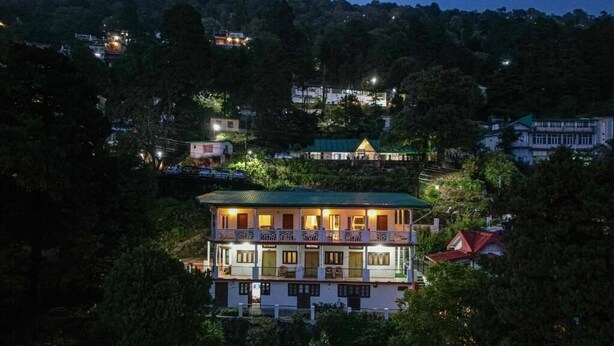 A multi-story building with balconies, surrounded by trees and other buildings. - Alaya Stays Headingly Suite Lake Facing (Nainital)