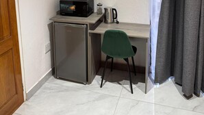 A compact room with a kitchenette, a small refrigerator, a microwave, a kettle, and a green chair. - Boutique Hotel-Style Room In Ferndale-A1 (Randburg)