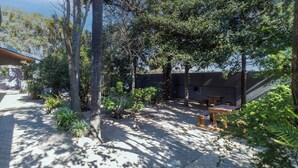 A courtyard with trees, a covered seating area, and a building with a sloped roof. - Boutique Hotel-Style Room In Ferndale-A1 (Randburg)