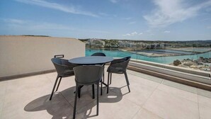 Une terrasse sur le toit, avec une table et des chaises, d’où l’on peut admirer une piscine et des bâtiments situés au loin.