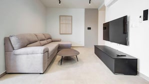 Un salon moderne avec un canapé, une table basse et un téléviseur à écran plat fixé au mur.