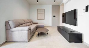 Ein modernes Wohnzimmer mit Sofa, Couchtisch und einem an der Wand befestigten Flachbildfernseher.