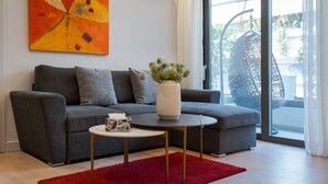 A modern living room with a grey sofa, a red rug, a white vase with greenery, and a large window with a view. - Alimos Escape 1 (Alimos)
