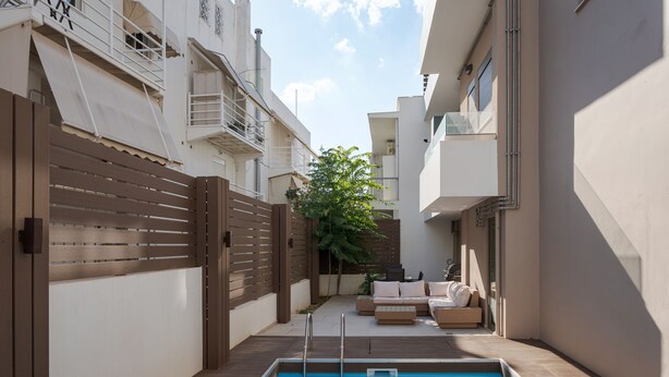 A swimming pool with a wooden deck, a fenced area, and a seating area with cushions. - Alimos Escape 1 (Alimos)