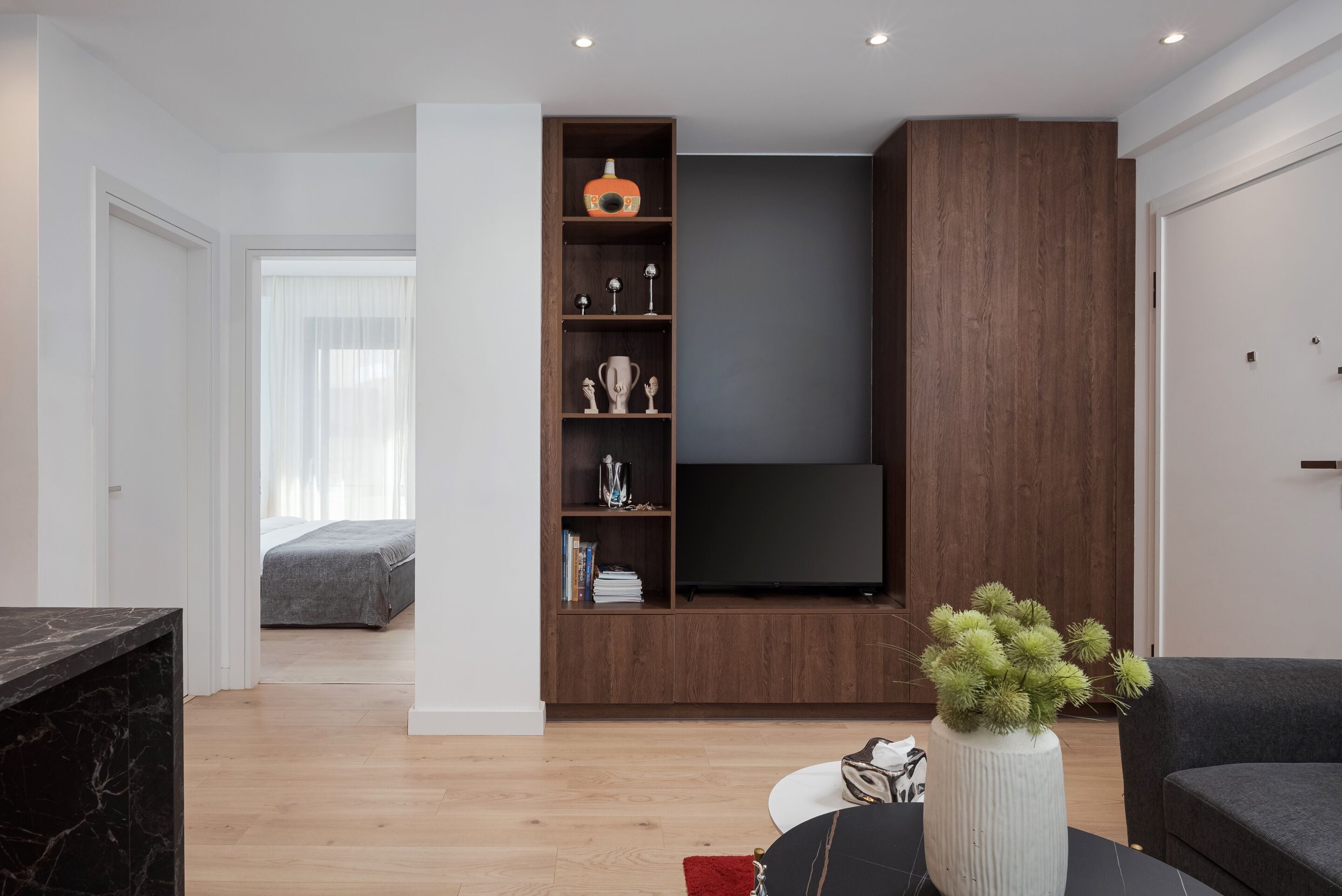 Un salon moderne avec un meuble TV en bois, une table en marbre et un canapé.