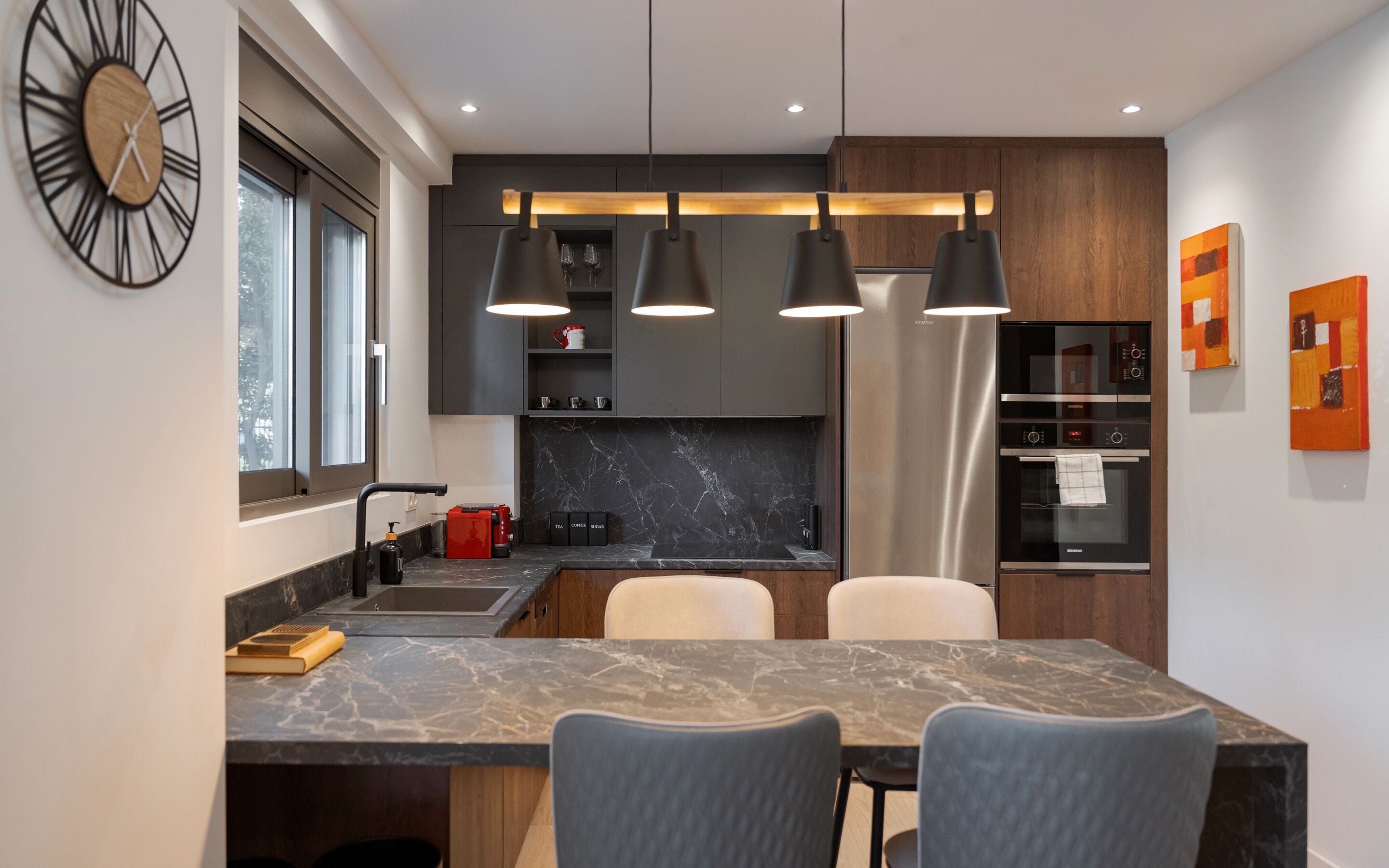A modern kitchen with a marble countertop, a built-in oven, and pendant lighting.