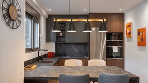 A modern kitchen with a marble countertop, a built-in oven, and pendant lighting. - Alimos Escape 1 (Alimos)