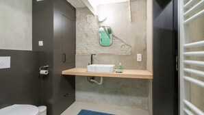 Un baño con inodoro, lavamanos, espejo y alfombra azul.