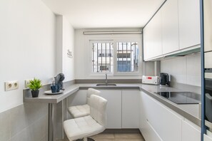 Eine kompakte Küche mit eingebautem Sitzplatz, einem Fenster mit Gitterstäben, einem Wasserkocher und einem Toaster.